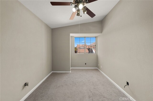 empty room featuring light colored carpet, vaulted ceiling, baseboards, and ceiling fan