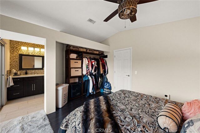 bedroom featuring a closet, visible vents, ensuite bathroom, vaulted ceiling, and light wood-type flooring