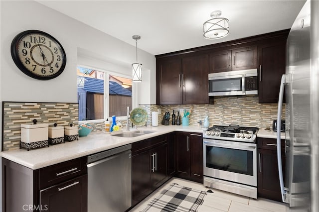 kitchen featuring pendant lighting, light countertops, appliances with stainless steel finishes, a sink, and dark brown cabinetry