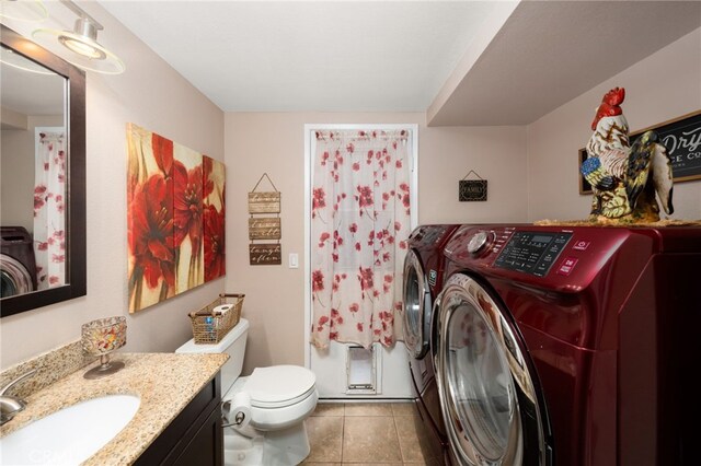 bathroom featuring toilet, tile patterned floors, vanity, and washing machine and clothes dryer