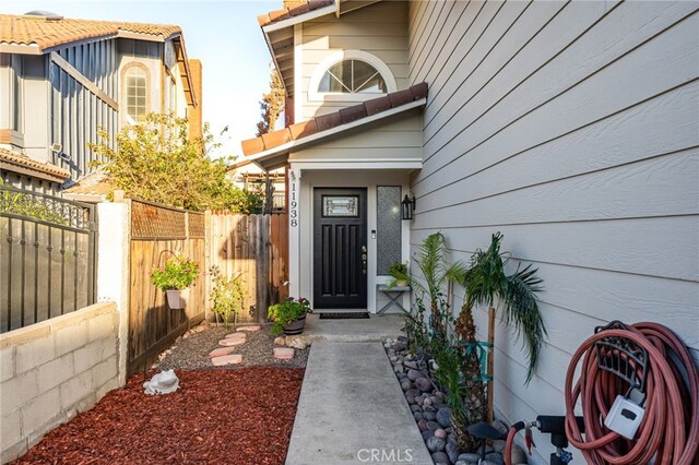 entrance to property with a tile roof and fence