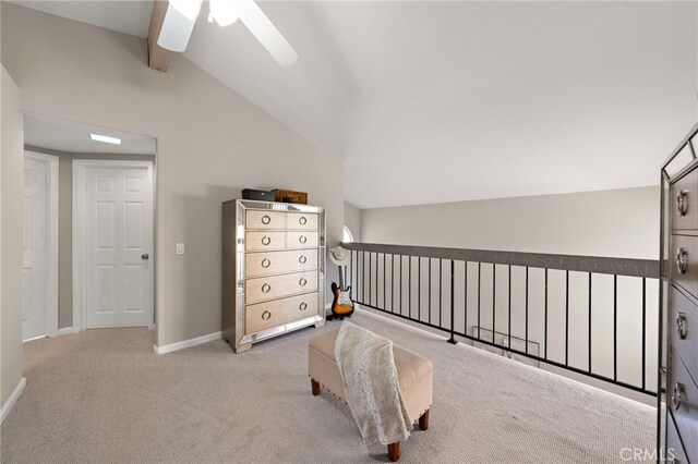 sitting room featuring a ceiling fan, light colored carpet, vaulted ceiling with beams, and baseboards