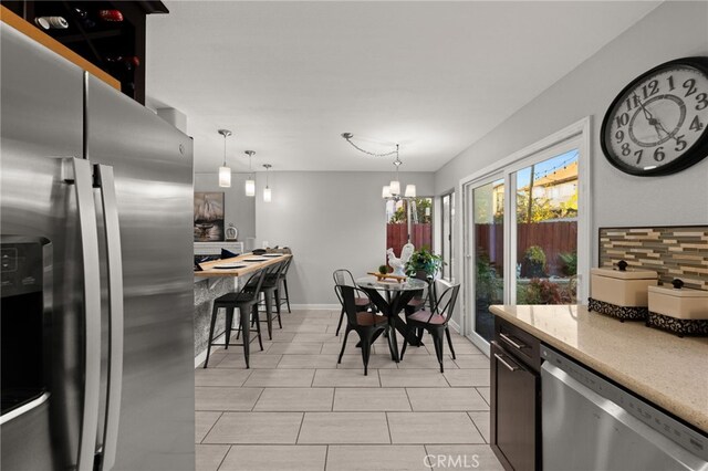 dining space with light tile patterned floors, baseboards, and a notable chandelier