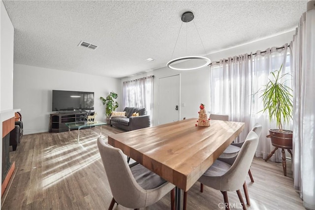 dining area featuring a textured ceiling and light hardwood / wood-style flooring