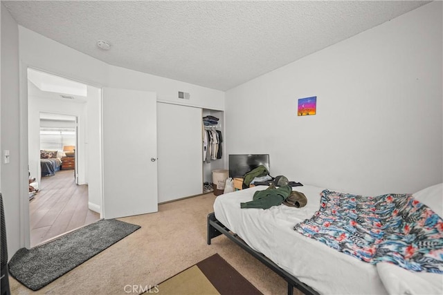 bedroom with light carpet, a closet, and a textured ceiling