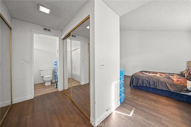 bedroom featuring a closet, a textured ceiling, connected bathroom, and hardwood / wood-style floors