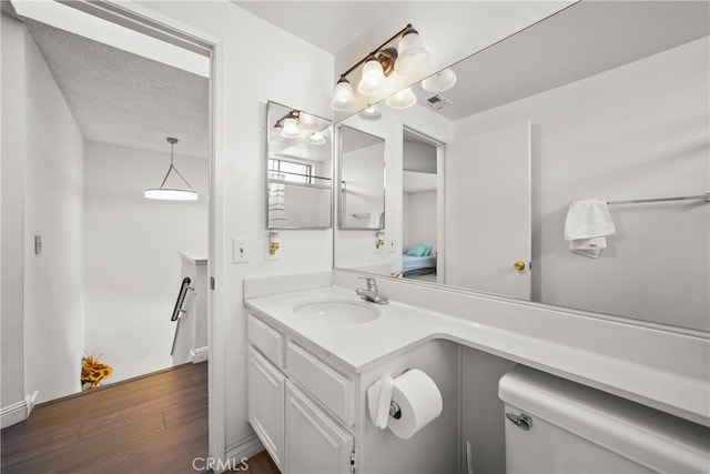 bathroom with hardwood / wood-style flooring, a textured ceiling, toilet, and vanity