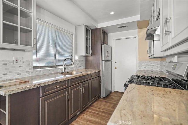 kitchen with light stone countertops, stove, sink, and stainless steel refrigerator