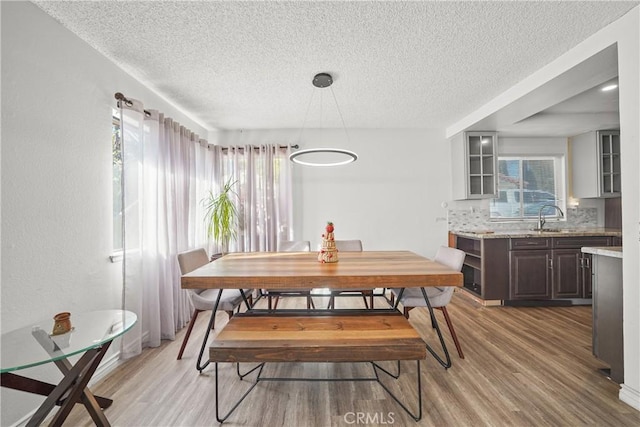 dining space with sink, a textured ceiling, and light wood-type flooring