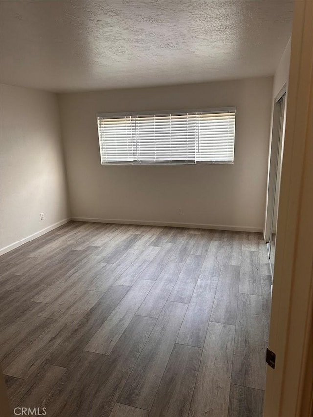 unfurnished room with hardwood / wood-style floors and a textured ceiling