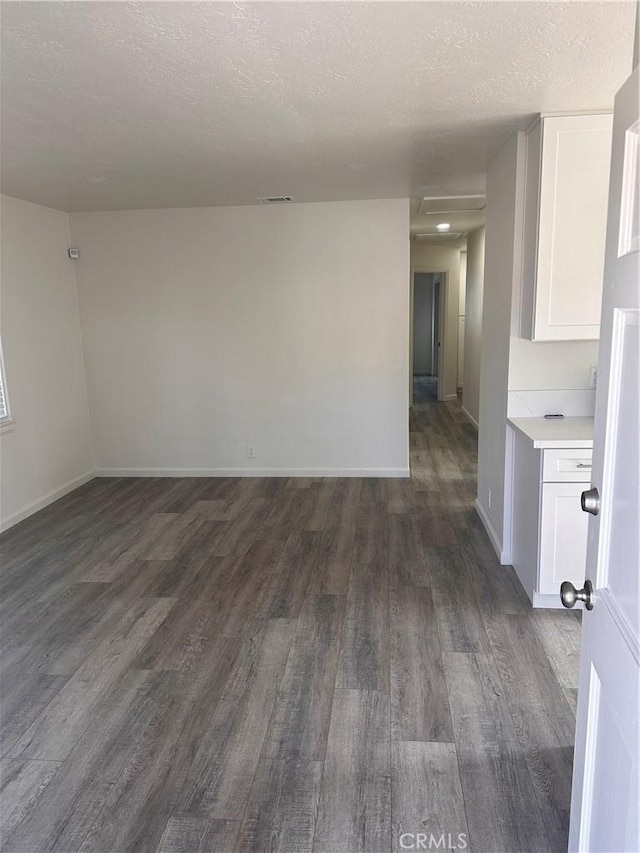 unfurnished room with dark wood-type flooring and a textured ceiling