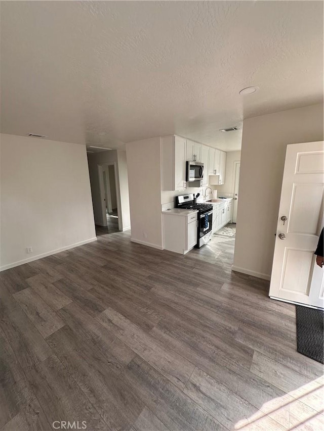 unfurnished living room with hardwood / wood-style flooring, sink, and a textured ceiling