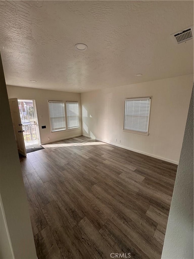 unfurnished living room with dark hardwood / wood-style floors and a textured ceiling