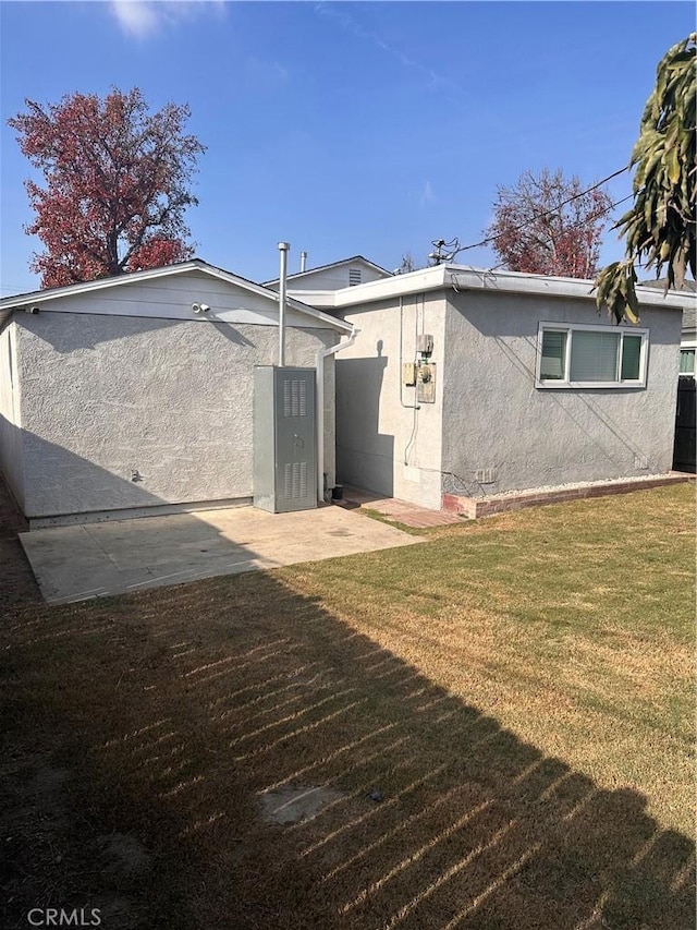 back of property featuring a lawn and stucco siding