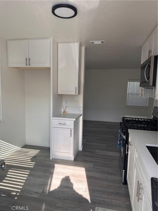 kitchen with stainless steel appliances, dark hardwood / wood-style floors, and white cabinets