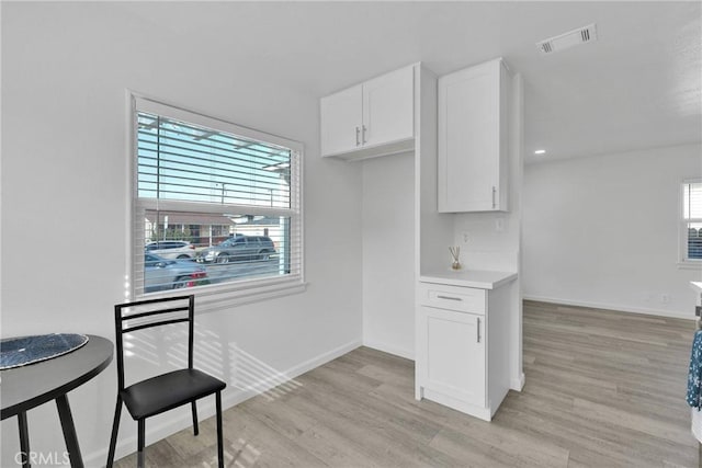 kitchen featuring light wood-style flooring, visible vents, baseboards, white cabinets, and light countertops