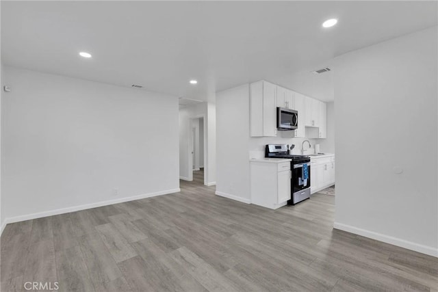 kitchen featuring appliances with stainless steel finishes, baseboards, light countertops, and light wood finished floors