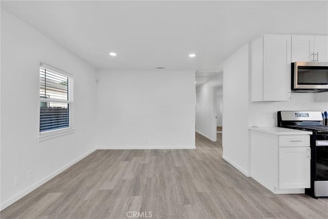 interior space with light wood finished floors, baseboards, white cabinetry, and stainless steel appliances