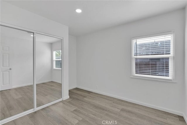 unfurnished bedroom with recessed lighting, a closet, baseboards, and wood finished floors