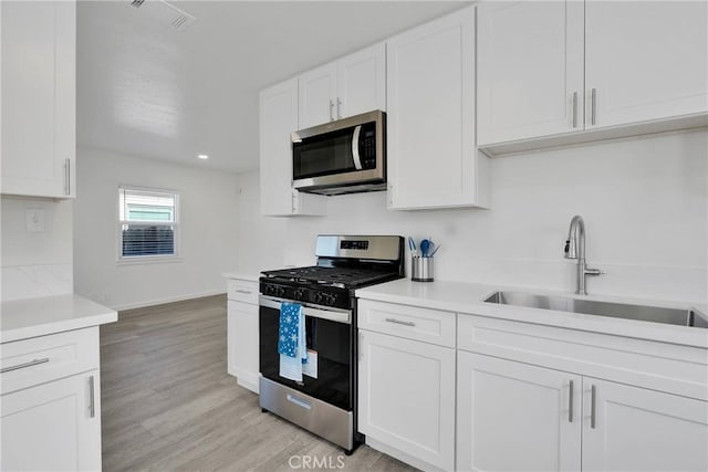 kitchen featuring light countertops, appliances with stainless steel finishes, a sink, and visible vents