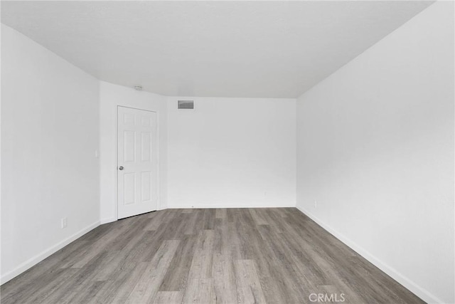 spare room with baseboards, visible vents, and wood finished floors