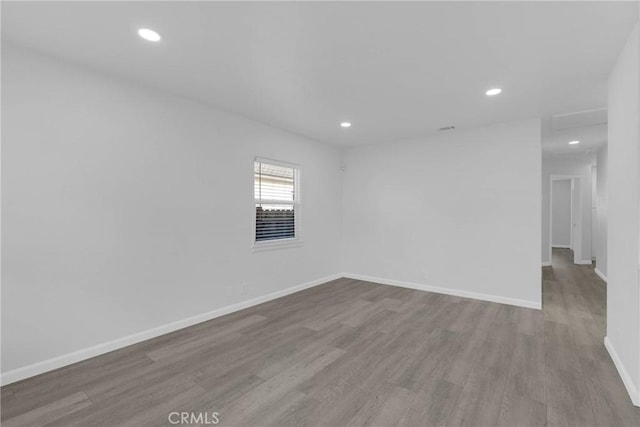 spare room with baseboards, wood finished floors, and recessed lighting