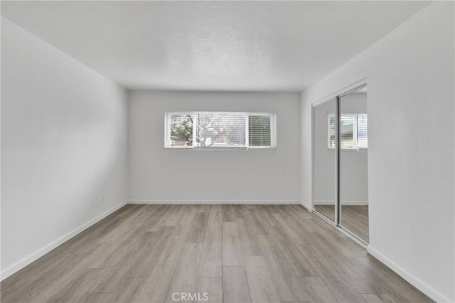 unfurnished bedroom with a closet, baseboards, and wood finished floors