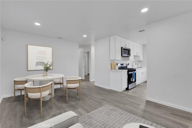 dining room with baseboards, light wood-style floors, visible vents, and recessed lighting