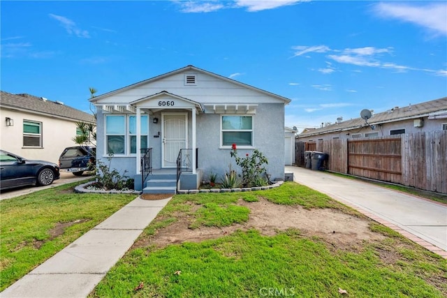 view of front of property with a front lawn, fence, and stucco siding