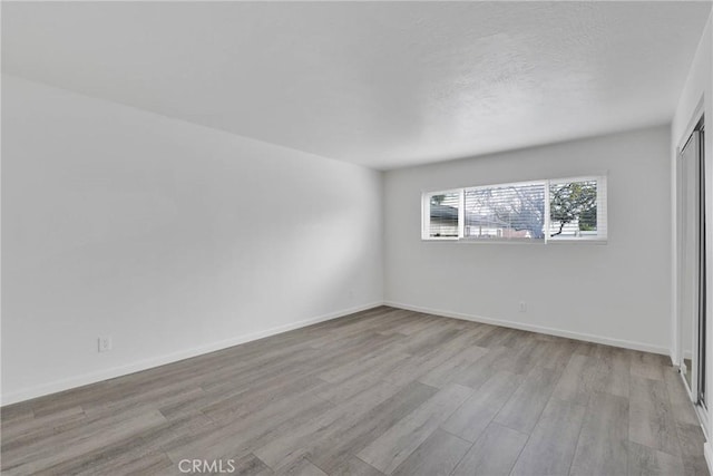 spare room featuring baseboards and wood finished floors