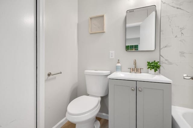 bathroom with a tub to relax in, toilet, tile walls, vanity, and hardwood / wood-style floors