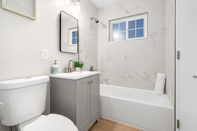 full bathroom with vanity, hardwood / wood-style floors, tiled shower / bath combo, and toilet