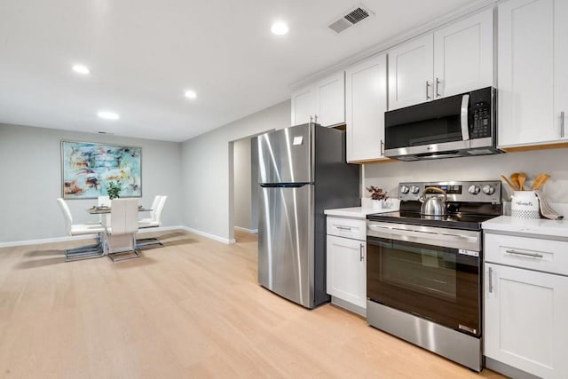 kitchen with appliances with stainless steel finishes, light wood-type flooring, and white cabinets