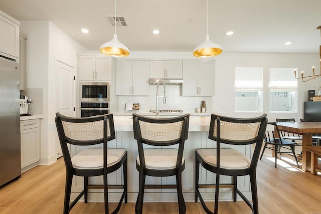 kitchen with hanging light fixtures, appliances with stainless steel finishes, and white cabinetry