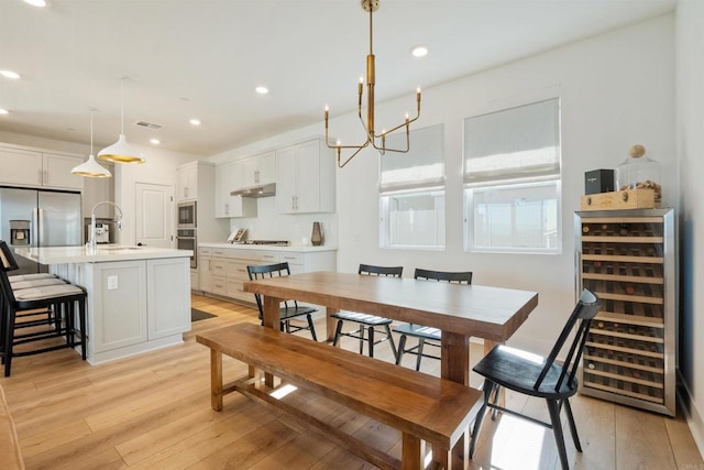 dining area with wine cooler, light wood-type flooring, and sink