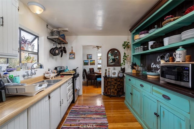 kitchen with ceiling fan, stainless steel appliances, light wood-type flooring, white cabinets, and sink