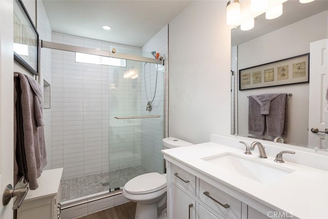 bathroom featuring toilet, vanity, a shower with door, and hardwood / wood-style flooring