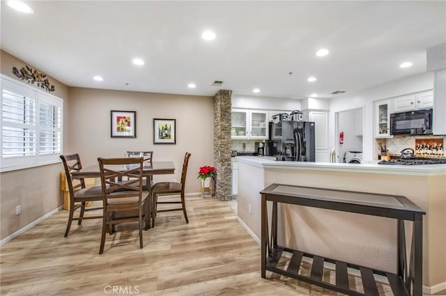 kitchen featuring decorative backsplash, white cabinets, black appliances, and light hardwood / wood-style flooring