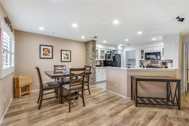 dining area with decorative columns and light wood-type flooring