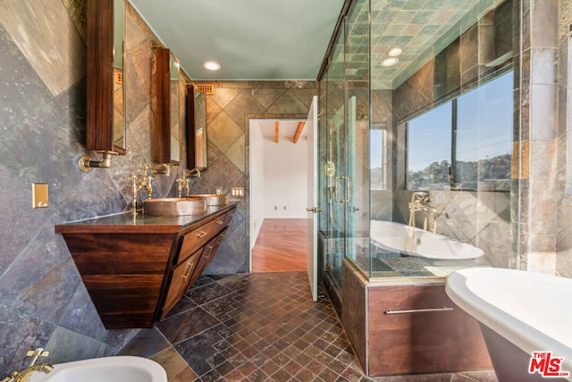 bathroom featuring a bidet, independent shower and bath, tile walls, and vanity