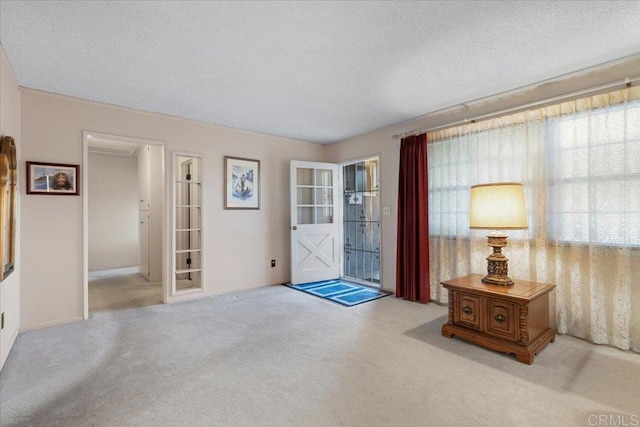 entryway featuring light carpet and a textured ceiling