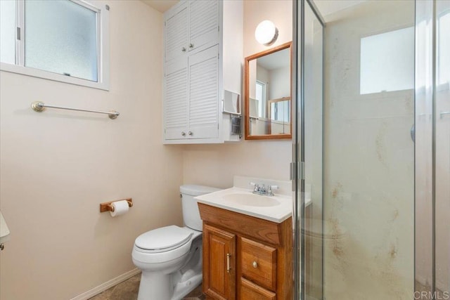 bathroom featuring toilet, a healthy amount of sunlight, vanity, and a shower with shower door