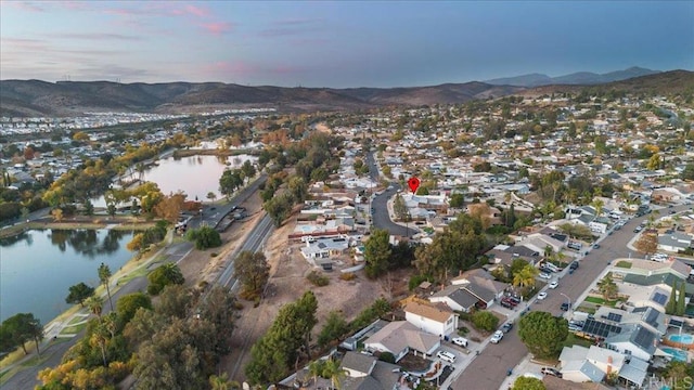 aerial view at dusk featuring a water and mountain view