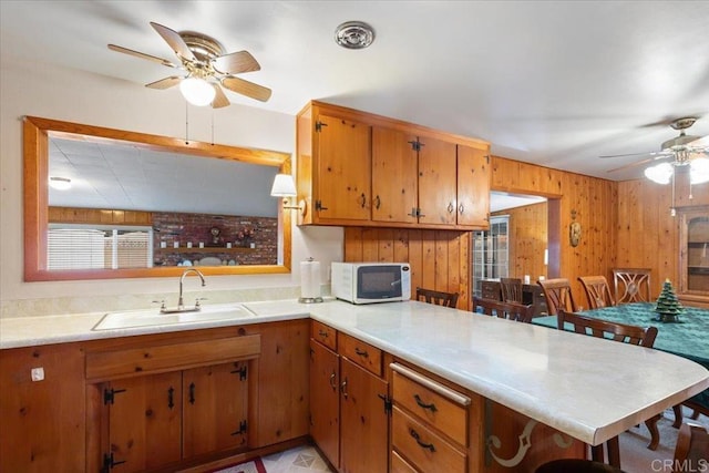 kitchen with ceiling fan, sink, kitchen peninsula, and a breakfast bar