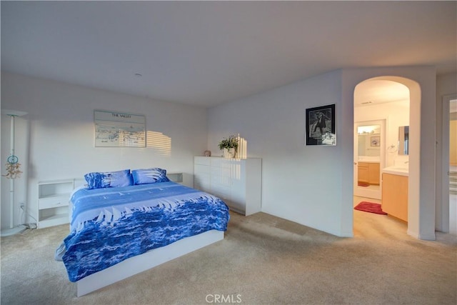 bedroom featuring ensuite bath and light colored carpet