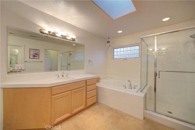 bathroom featuring vanity, a skylight, and separate shower and tub