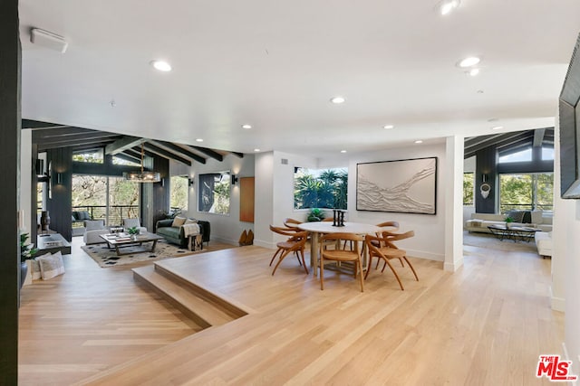 dining room featuring light hardwood / wood-style flooring and vaulted ceiling with beams