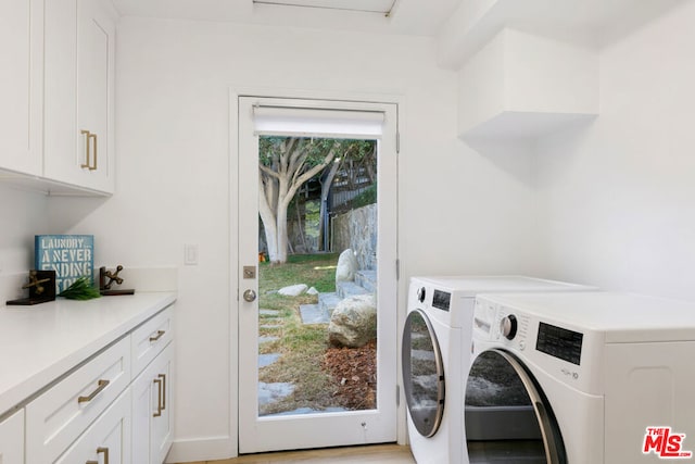 clothes washing area featuring washer and dryer, plenty of natural light, and cabinets