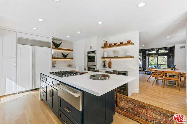 kitchen featuring white cabinetry, appliances with stainless steel finishes, light hardwood / wood-style flooring, and a kitchen island