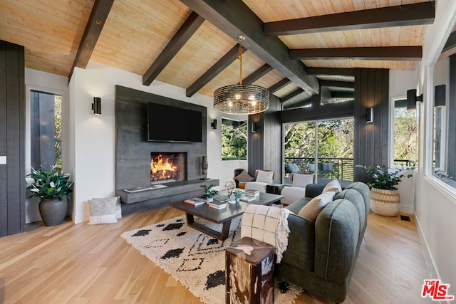 living room with vaulted ceiling with beams, a large fireplace, wood ceiling, and light hardwood / wood-style flooring